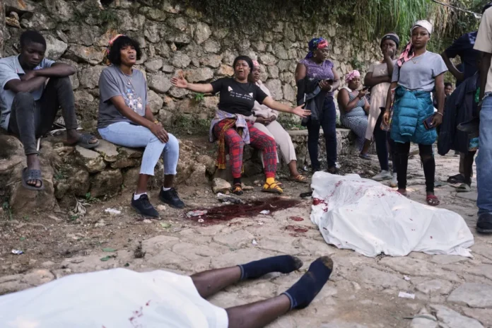 Varias personas se reúnen junto a los cuerpos de quienes, según dijeron, eran sus familiares y fueron asesinados en un ataque de pandillas en el barrio de Kenscoff, el lunes 24 de agosto de 2026, en Puerto Príncipe, Haití. (AP Foto/Odelyn Joseph) License this photo